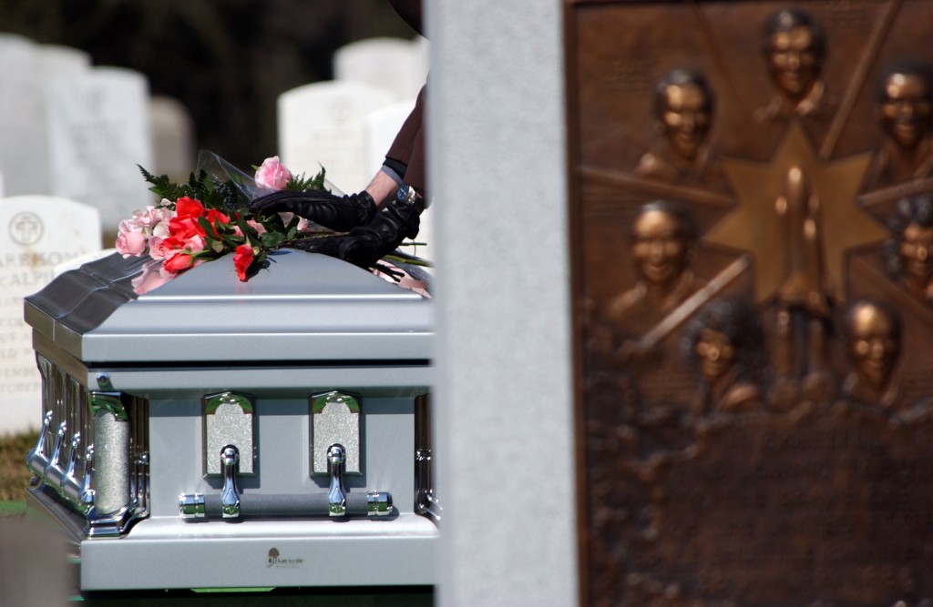 man placing hand on funeral casket